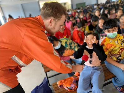 Teacher in Thailand handing a smiling student a microphone 