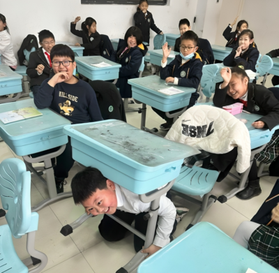 Students in China smiling and messing around in their classroom 