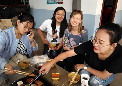 English teacher sharing her meal with colleagues in China, and smiling 