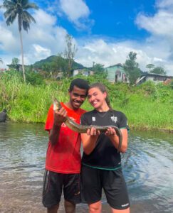 Girl and local man smiling with a fish in Fiji 