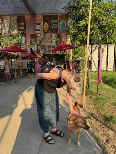 Older lady from the UK patting a dog in Thailand. 