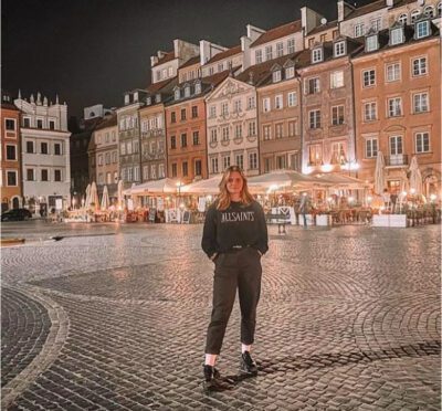 Girl standing in Warsaw's old town at night